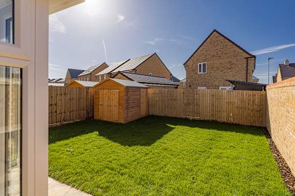 A backyard with a wooden fence and a green lawn.