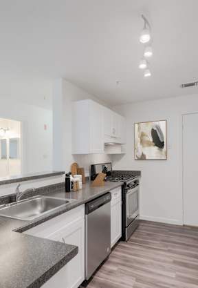 a kitchen with white cabinets and granite countertops  at Residences at Westborough Station, Westborough