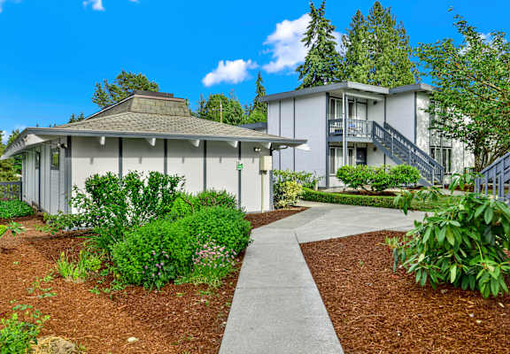 A modern house with a grey roof and a grey walkway in front of it.