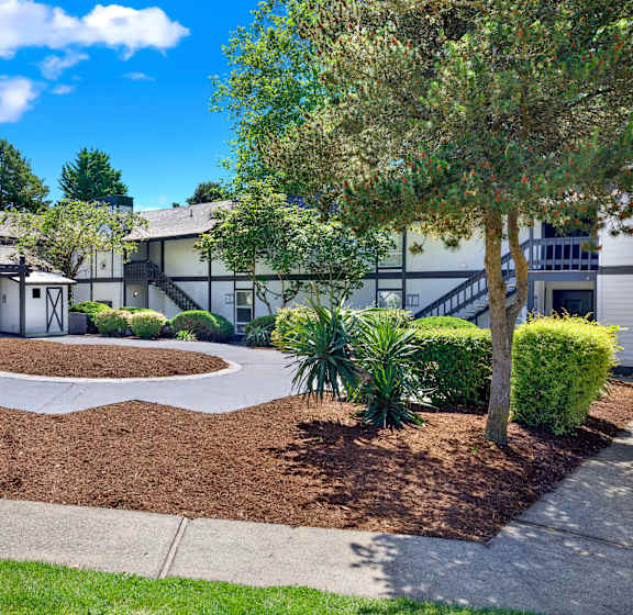 A building with a landscaped front yard and a tree.