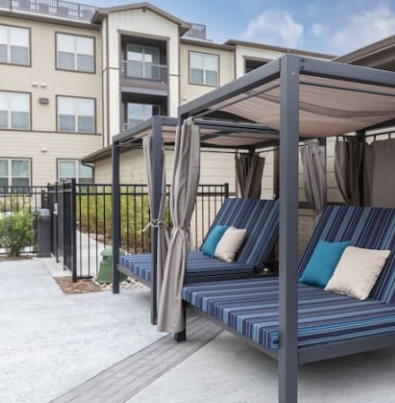 a patio with a canopy bed in front of an apartment building