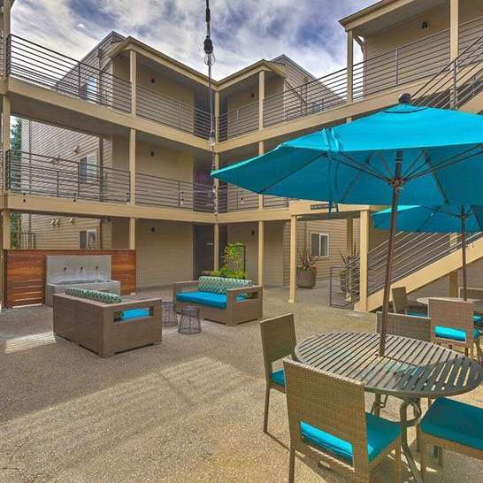 a patio with an umbrella and tables and chairs