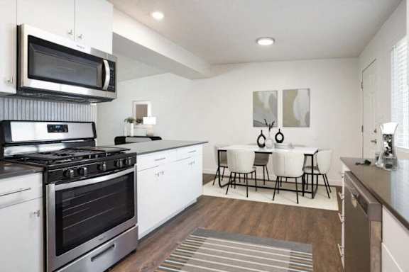 A modern kitchen with white appliances and a dining table set for four.