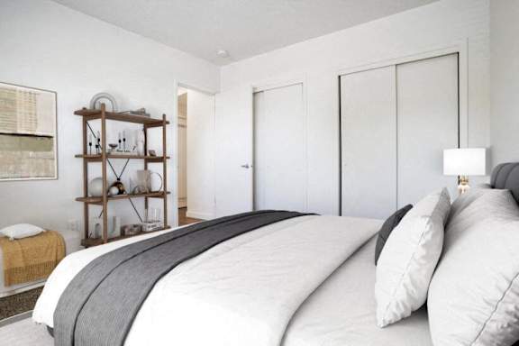 A bedroom with a large bed and a wooden shelf.