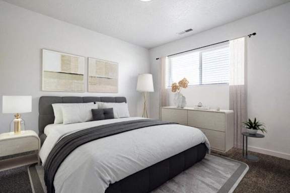 A well-lit bedroom with a large bed and a nightstand with a lamp.