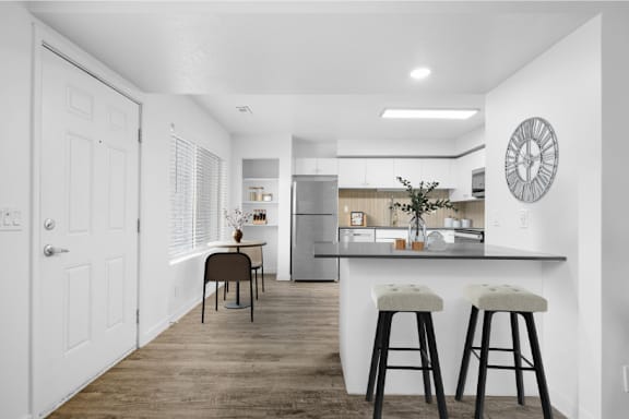 A kitchen with a bar stool and a clock on the wall.