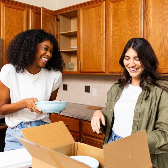 two people in a kitchen preparing food in a box