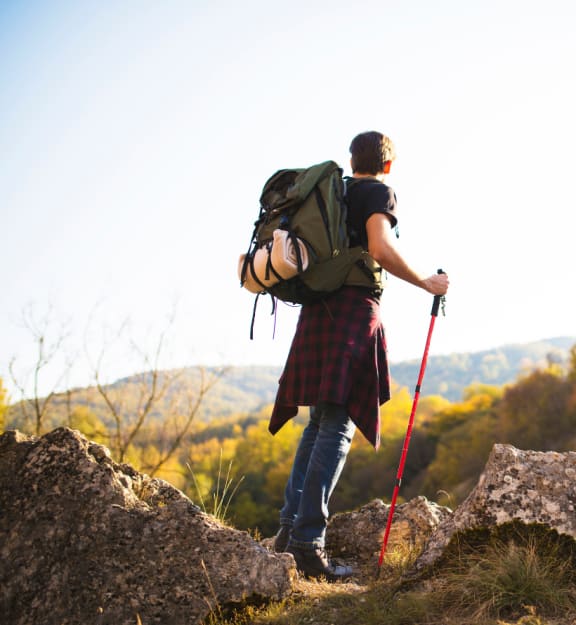A person with a backpack and walking stick stands on a rocky outcrop. at Yellowstone Landing, Montana, 59714