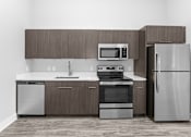 Thumbnail 4 of 10 - A modern kitchen with a refrigerator, sink, oven, and microwave.