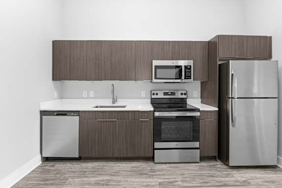 A modern kitchen with a refrigerator, sink, oven, and microwave.