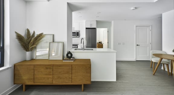 a kitchen and living room with white walls and a wooden dresser