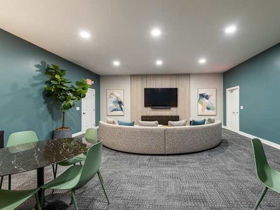 A modern living room with a grey carpet and a round sofa.