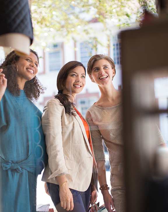 Three women are standing together and smiling.