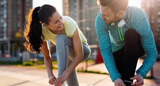 a man and woman tying their shoes while kneeling down