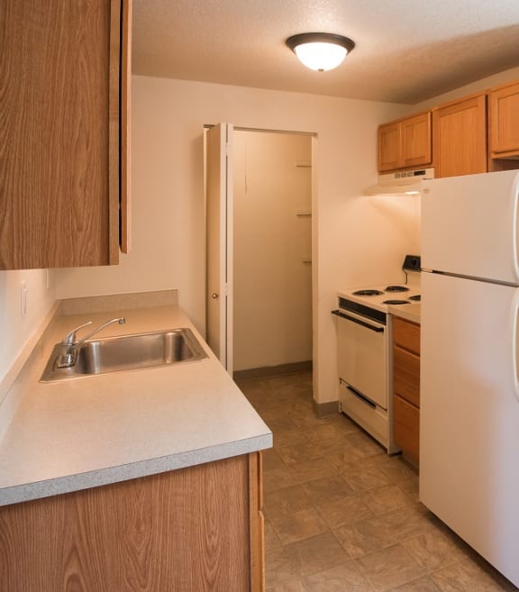 a kitchen with a white refrigerator freezer next to a white stove top oven
