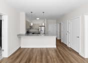 Thumbnail 5 of 8 - A kitchen with white cabinets and a wooden floor.