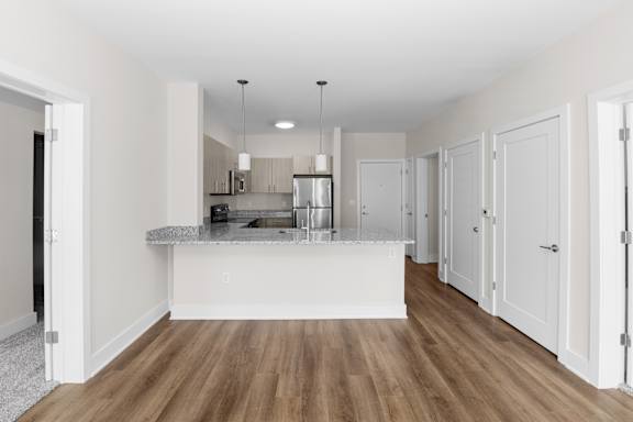 A kitchen with white cabinets and a wooden floor.