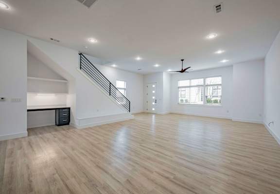 A spacious room with wooden flooring and a staircase.