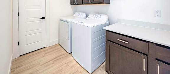 A white door is on the left of a laundry room.