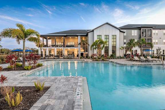 A large swimming pool in front of a resort style building.