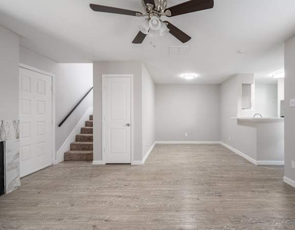 A spacious room with a ceiling fan and lighting fixtures.