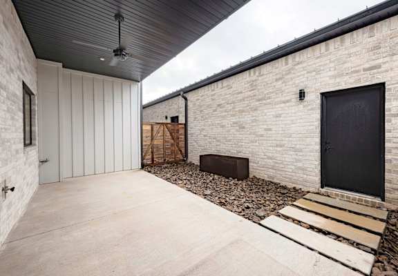 A modern house with a black door and a black ceiling fan.