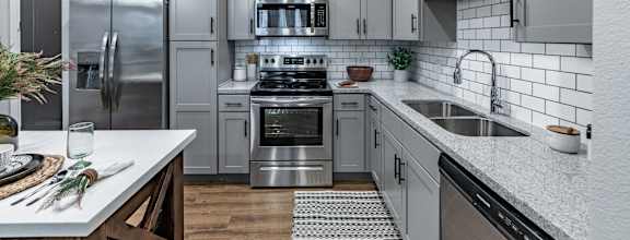 A modern kitchen with stainless steel appliances and white countertops.