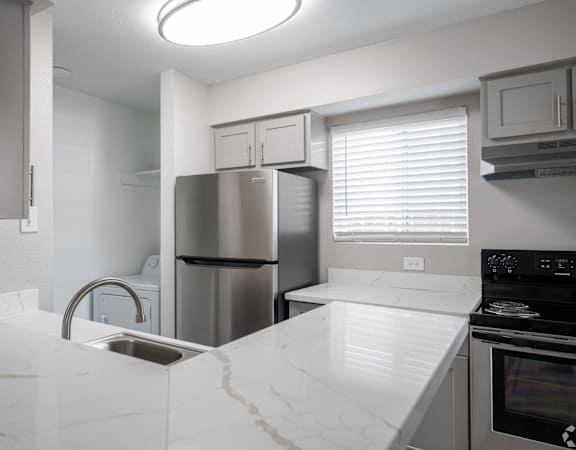 A kitchen with a white counter top and stainless steel appliances.