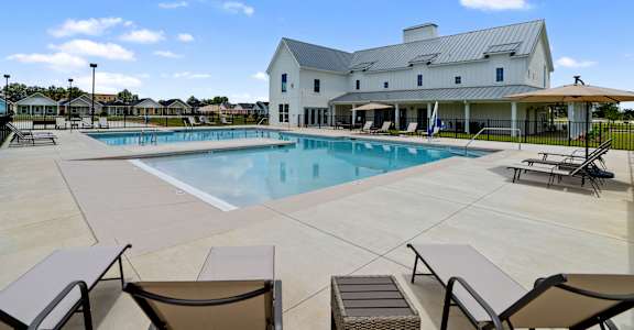 a swimming pool with chairs and a building in the background