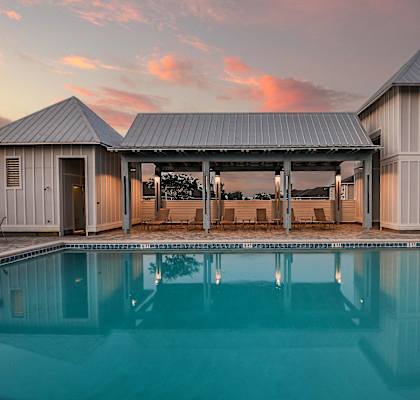 a swimming pool in front of a building with a sunset in the background