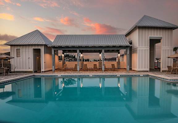a swimming pool in front of a building with a sunset in the background