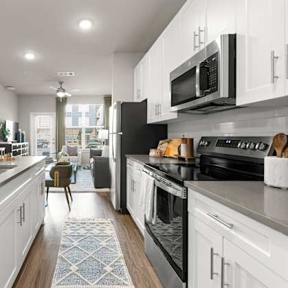 A modern kitchen with white cabinets and black appliances.