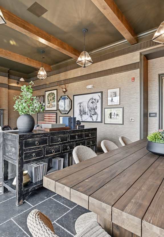 A wooden table is surrounded by chairs in a room with a fireplace.
