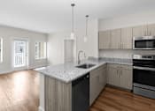 Thumbnail 2 of 8 - A kitchen with a granite countertop and stainless steel appliances.