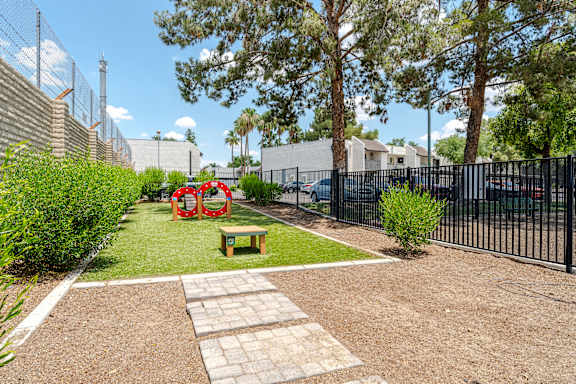 A small garden with a bench and a red sculpture.