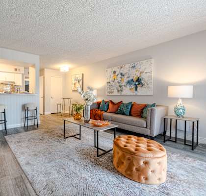 A living room with a grey sofa, a white coffee table, and a pink ottoman.