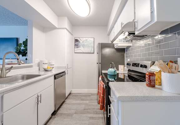 A modern kitchen with white cabinets and a grey countertop.