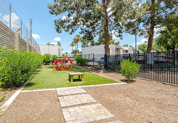 A small garden with a bench and a red sculpture.