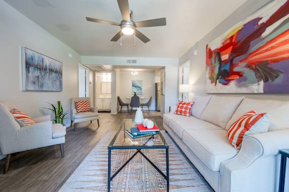 A living room with a white couch, a coffee table, and a ceiling fan.