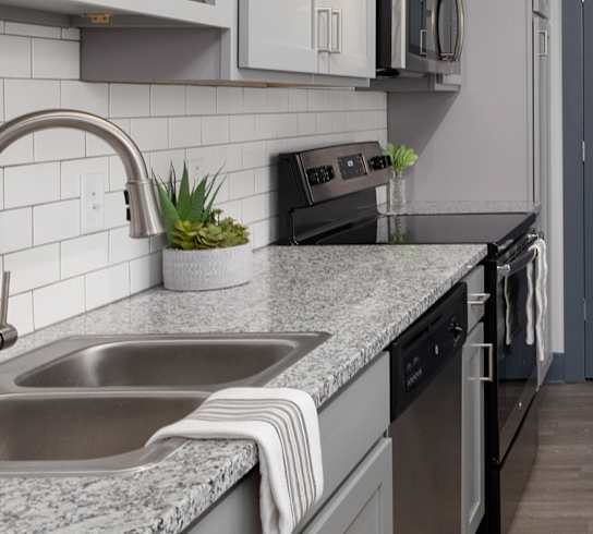 A modern kitchen with a grey countertop and white cabinets.