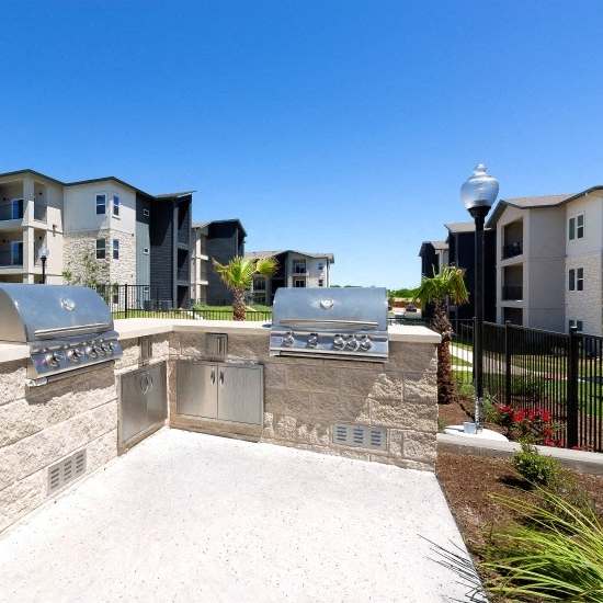 A pool with a stone fence and a building in the background.