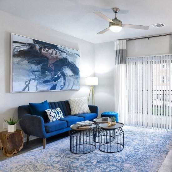 A living room with a blue sofa and a painting on the wall.