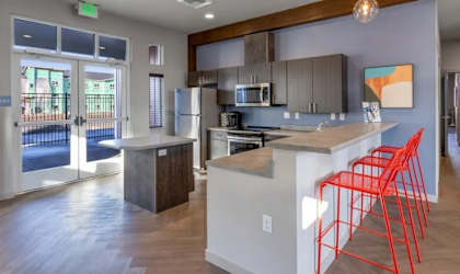 A kitchen with a white island and red chairs.