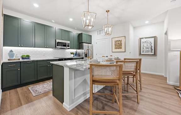 A kitchen with green cabinets and a white island.