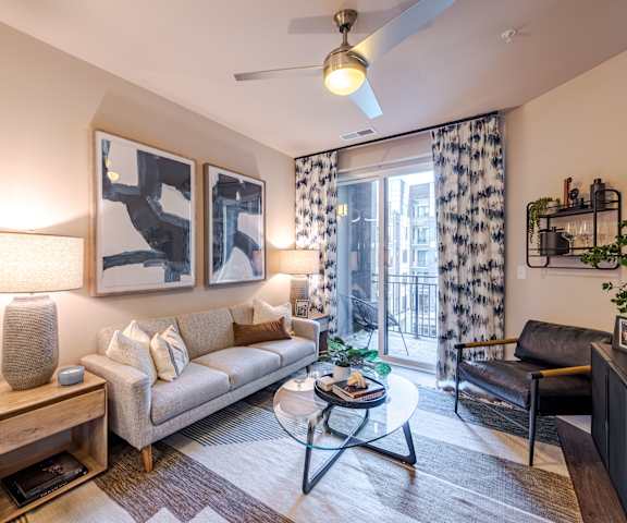 A living room with a couch, a coffee table, and a ceiling fan at The Edison Lofts Apartments, Raleigh, NC