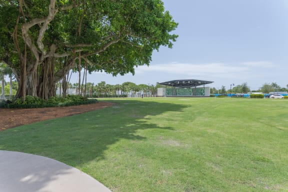 a large grassy area with trees and a pavilion in the background