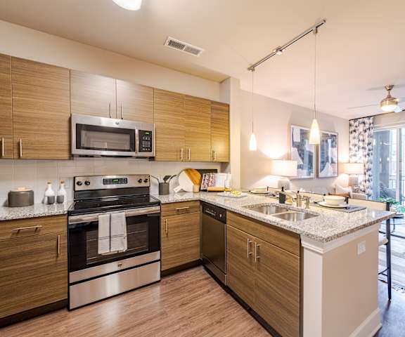 A modern kitchen with wooden cabinets and stainless steel appliances at The Edison Lofts Apartments, Raleigh, 27601