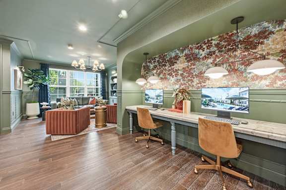 A room with a desk and chairs with a leafy wallpaper.