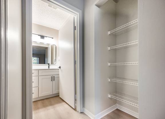 A white pantry with a door open to a bathroom.