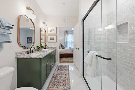 A bathroom with a green vanity and a glass shower.